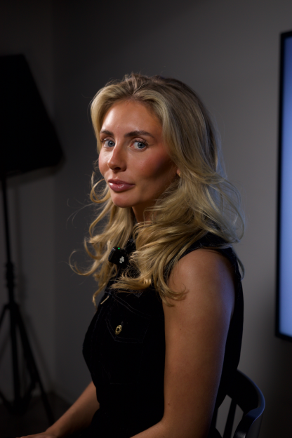 Woman with blonde hair wearing a black vest.