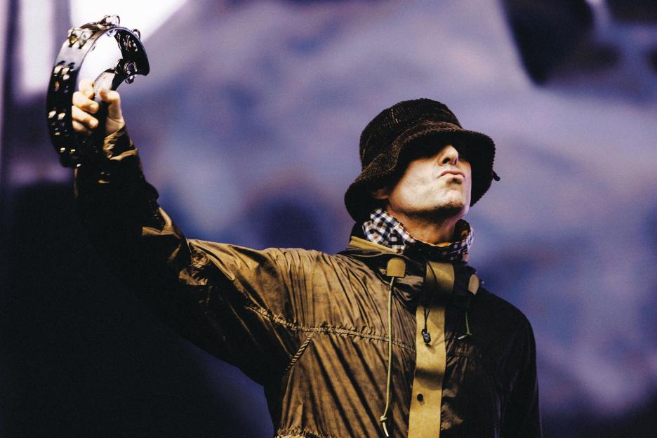 Liam Gallagher playing a tambourine.
