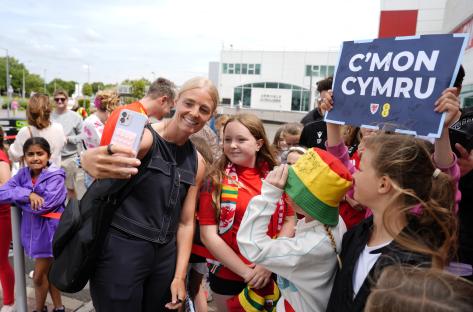 Sophie Ingle taking selfies with Wales fans at an airport.
