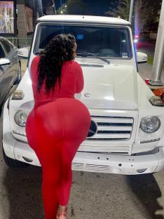 Woman in red outfit posing in front of a white SUV.