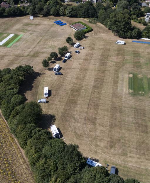 Aerial view of caravans parked on a cricket pitch.