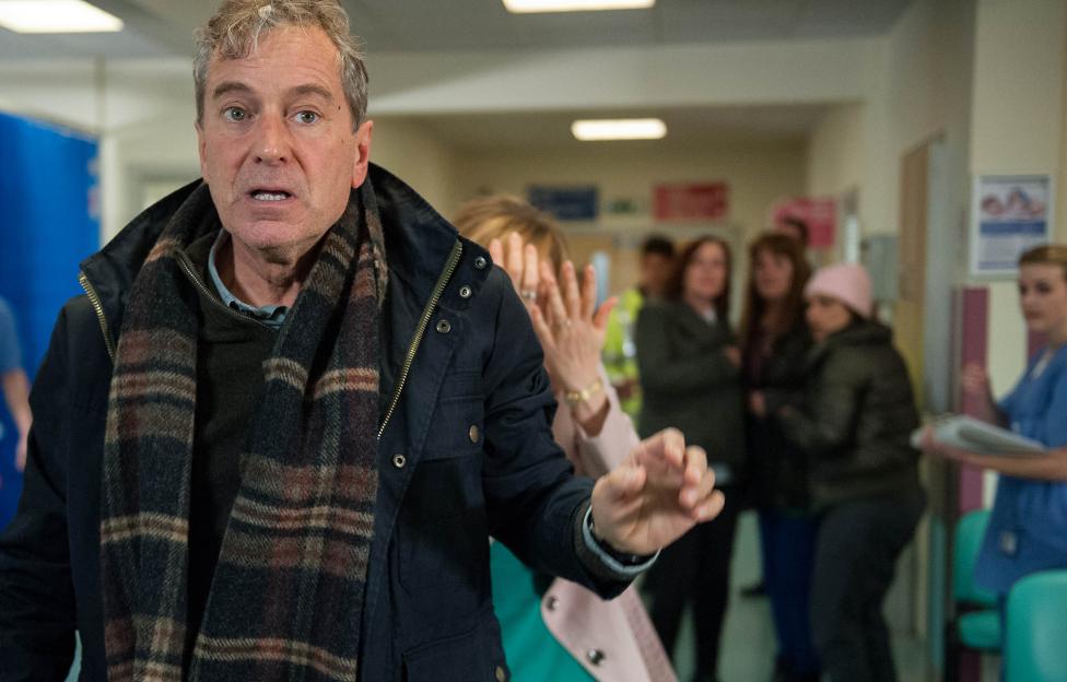 A man in a distressed state in a hospital hallway.