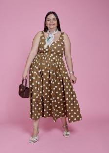Woman in brown polka dot dress and white sandals.