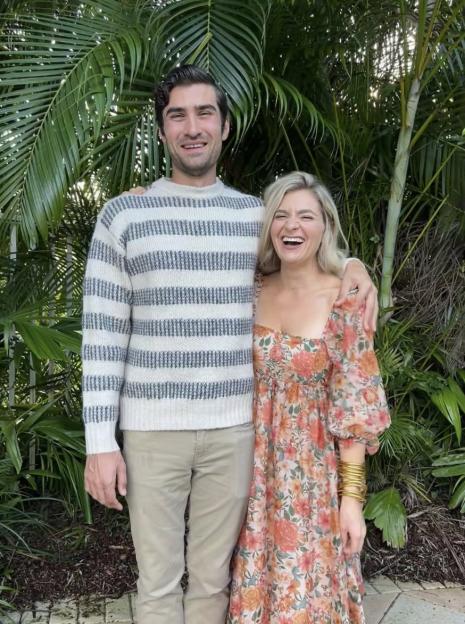 Couple standing together in front of tropical plants.