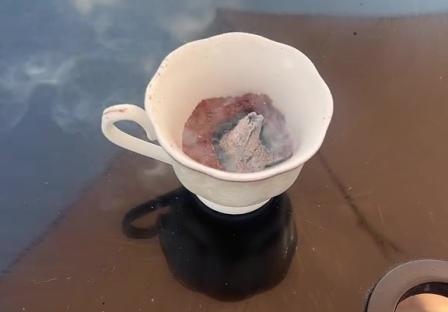 A teacup with smoldering material inside, used to repel flies.