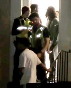 Police officers speaking with students at a noisy house party.