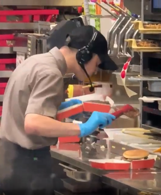 Fast food worker assembling a burger.
