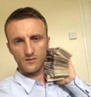 Ardi Beshiri holding a large stack of cash.
