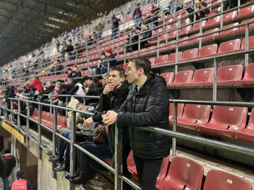 Two men leaning on a railing in a stadium.