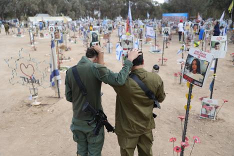 Two Israeli soldiers comfort each other at a memorial site for victims of the 2023 Supernova music festival attack.