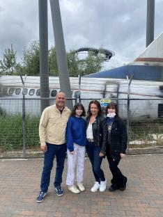 Family posing in front of a wrecked airplane at an amusement park.