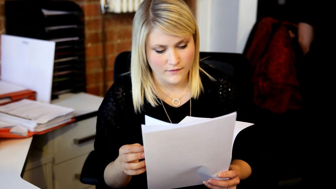 Woman reviewing documents at her desk.