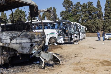 Burned and damaged buses in a parking lot.