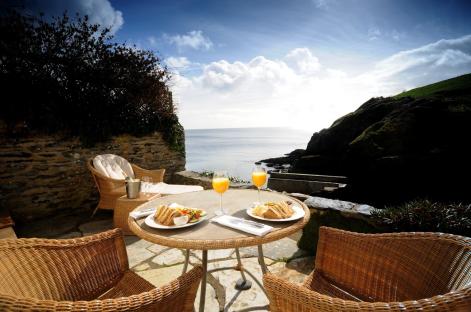 Ocean view breakfast setting with sandwiches and orange juice.