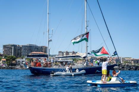Sailboat with Palestinian flags and people on board.