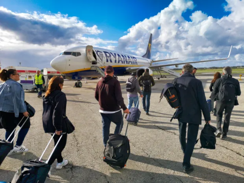 Passengers with luggage walking toward a Ryanair plane.