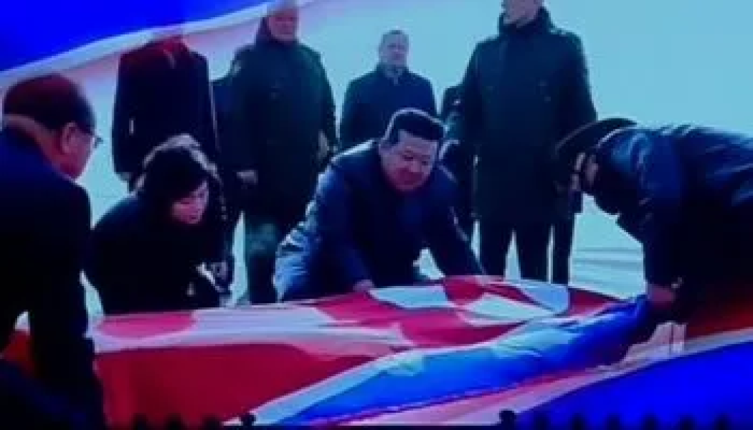 Kim Jong-un and others unfolding a large flag.