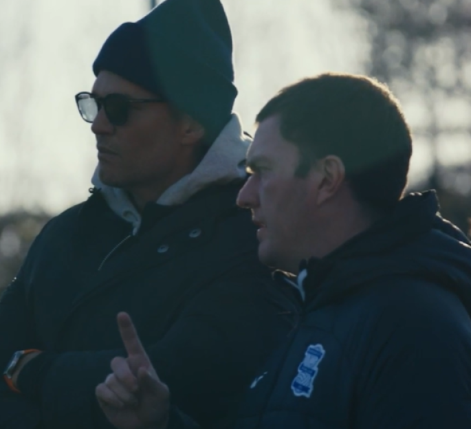 Two men in winter clothing, one gesturing.