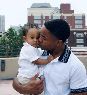 A father kissing his baby on the cheek.