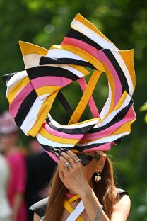Woman wearing a large, multi-colored hat at Royal Ascot.
