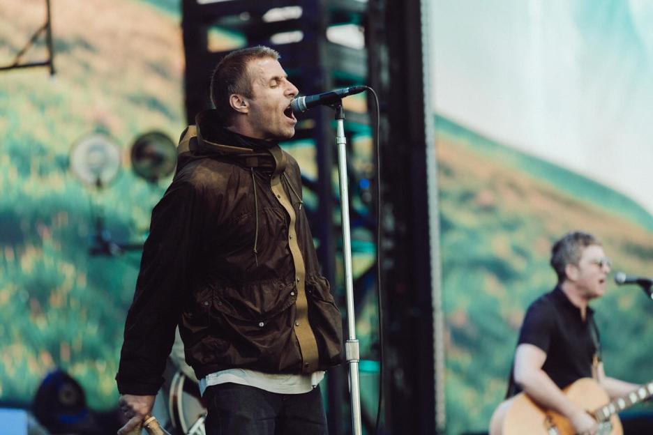 Liam Gallagher singing into a microphone on stage.