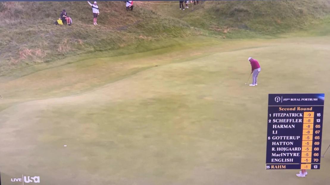 Golfer putting on a green with scoreboard.