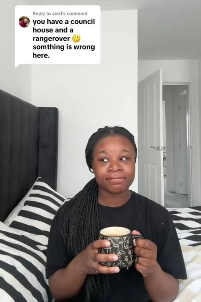 Woman holding a mug while responding to a comment about living in a council house and owning a Range Rover.