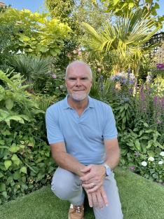 Man kneeling in a garden.