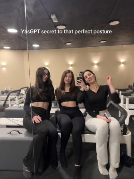 Three women in workout attire sitting in a Pilates studio.