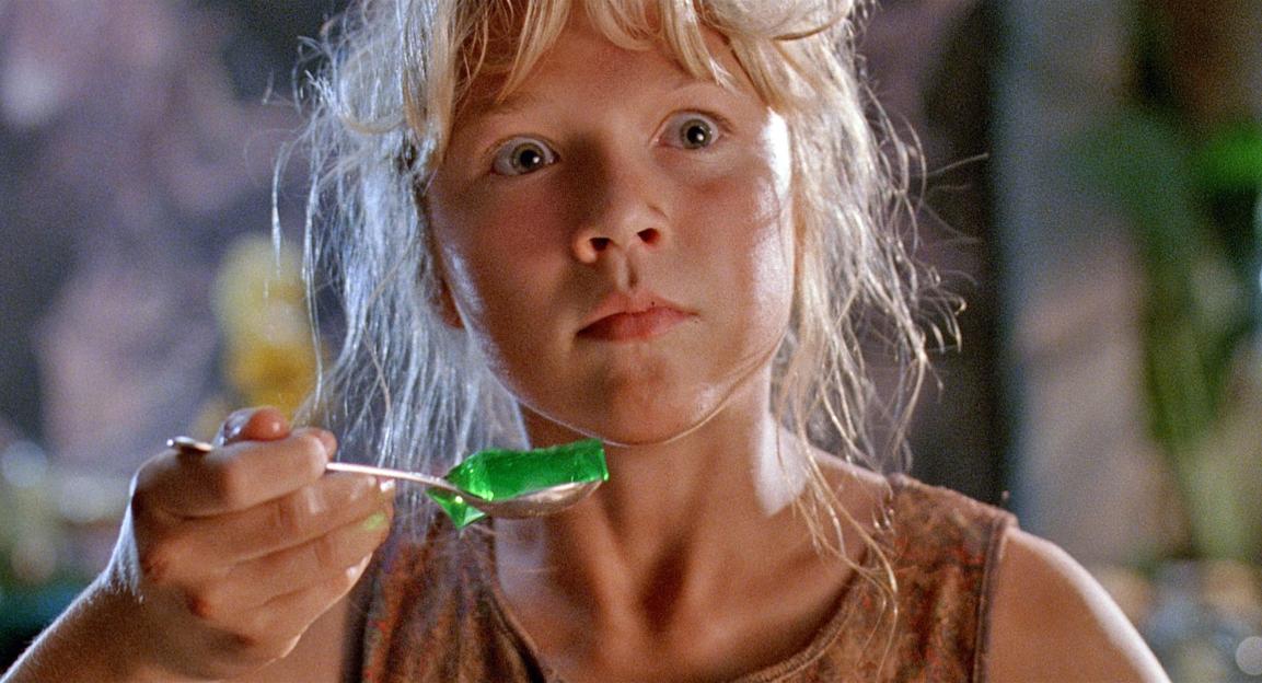 Girl eating green gelatin from a spoon.