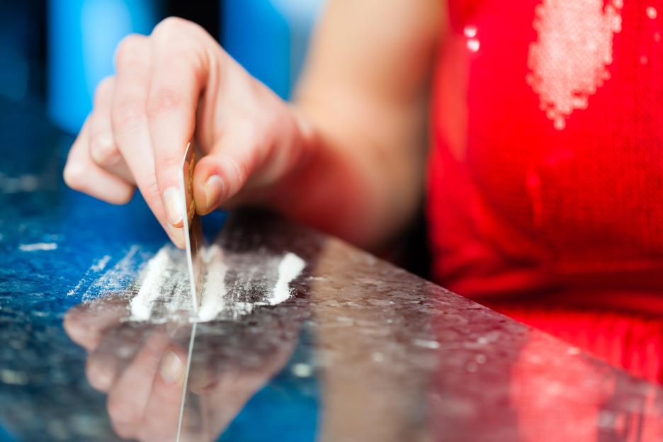 Close-up of a young woman snorting cocaine using a credit card.