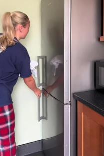 Person cleaning a stainless steel refrigerator.