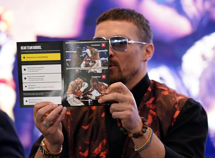 Oleksandr Usyk holding a boxing rules leaflet.