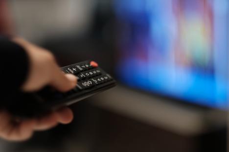 A hand holding a TV remote, changing channels.