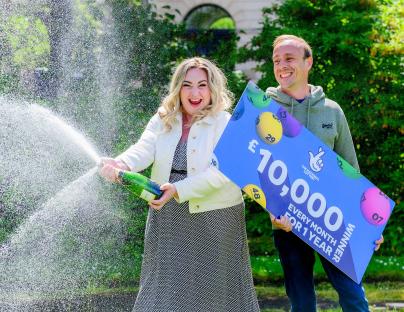 Lottery winners celebrating with champagne and a large check.