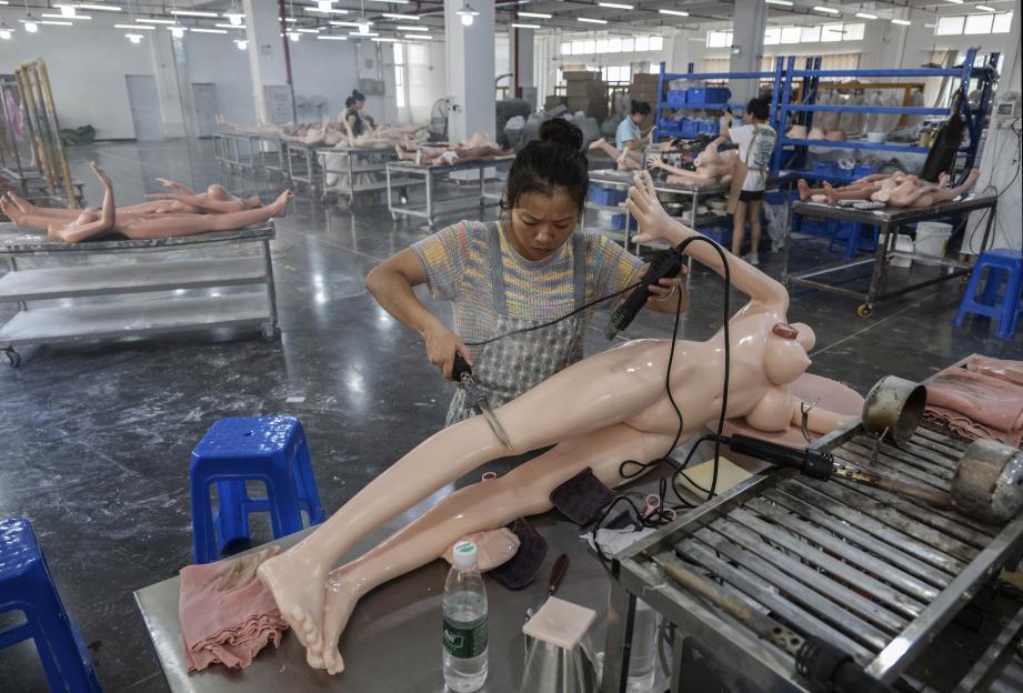 A worker finishes the skin of a silicone sex doll in a factory.