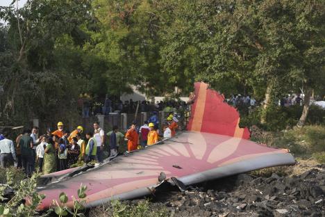 Debris of a crashed airplane with people standing nearby.