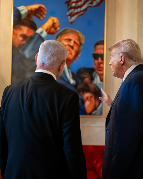 Two men in suits view a painting of a crowd and an American flag.