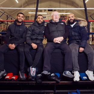 Four men, three of whom are brothers, sitting together in a boxing gym.