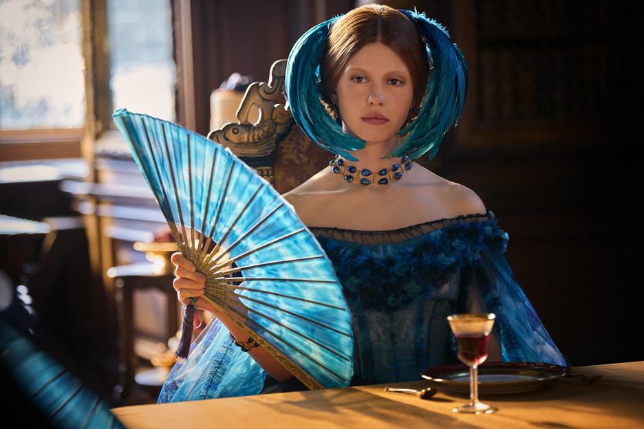 Mia Goth as Elizabeth in Frankenstein, holding a blue fan.