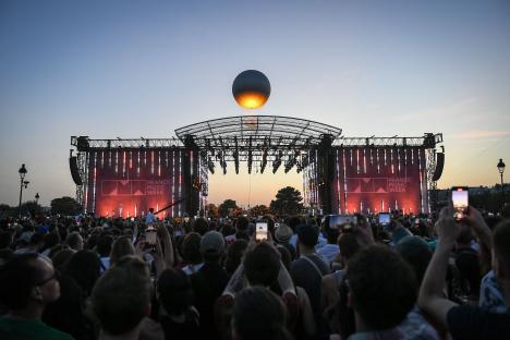 A hot air balloon shaped like the Paris 2024 Olympic cauldron floats above a concert at the Tuileries Garden in Paris.