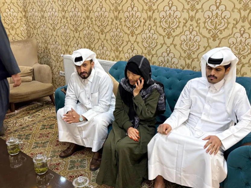 Three people in traditional Middle Eastern clothing seated on a teal couch.