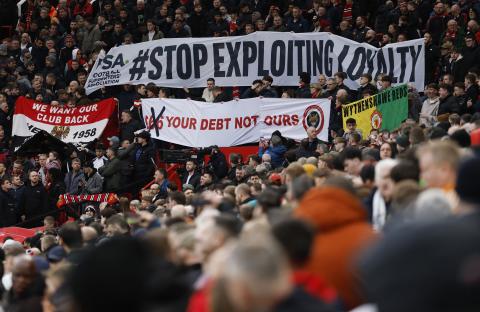 Manchester United fans holding banners protesting against the club's ownership.