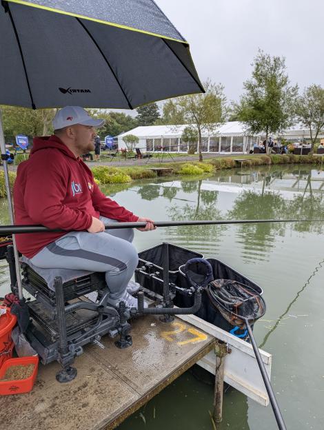 Angler fishing from a platform under an umbrella.