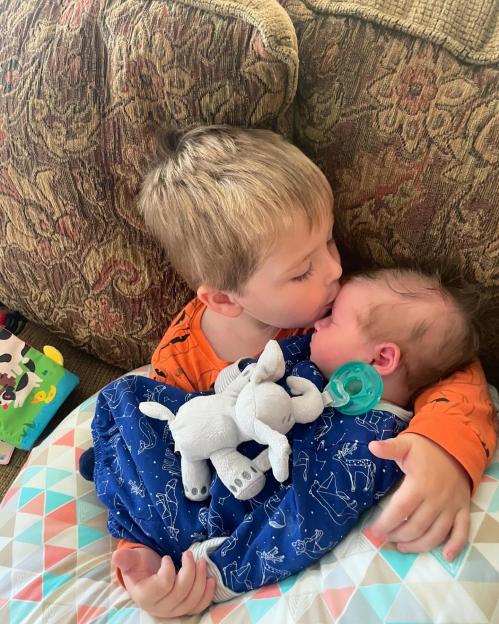 Older brother kissing his baby brother.
