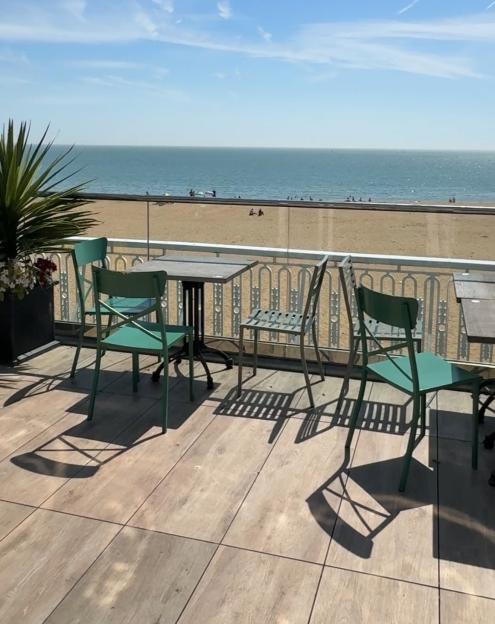 Ocean view from a patio with tables and chairs.