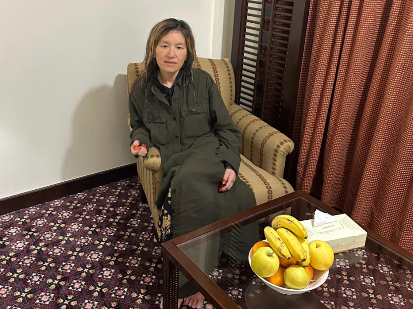 Woman sitting in armchair with fruit bowl on coffee table.