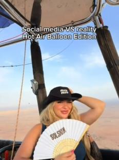 Woman in hot air balloon holding hand fan.