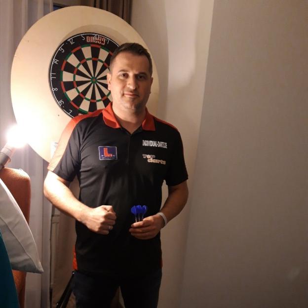 Man holding darts in front of a dartboard.
