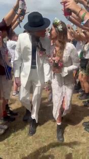 Couple getting married at a festival with a large crowd cheering.
